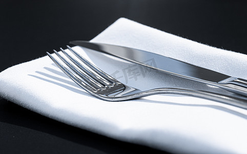 精美菜单摄影照片_户外豪华餐厅餐桌上配有白色餐巾的叉子和刀、婚礼或活动的精美餐饮菜单以及餐饮服务理念