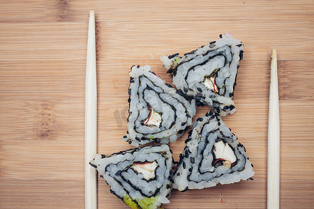 日本厨房摄影照片_三角形寿司卷筷子木质背景日本厨房