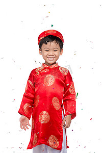 穿着红色奥黛的快乐越南男孩用五彩纸屑庆祝新年。