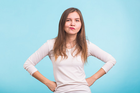 生气愤怒脾气暴躁的年轻悲观女人态度恶劣思考看着你消极的人类情感面部表情在蓝色背景上的感觉反应