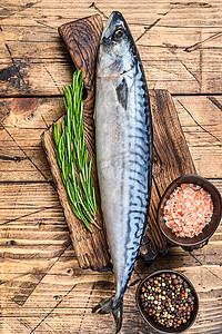 咸水杂鱼煲摄影照片_未加工的咸水鱼鲭鱼在木切板上与百里香。