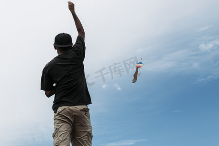 举手小男孩摄影照片_一个小男孩在河岸上放风筝的照片