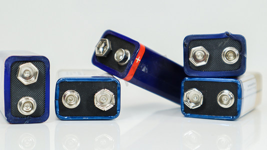 白色背景上使用了五个蓝色、混乱排列和分散的 PP3 电池，带有反射。