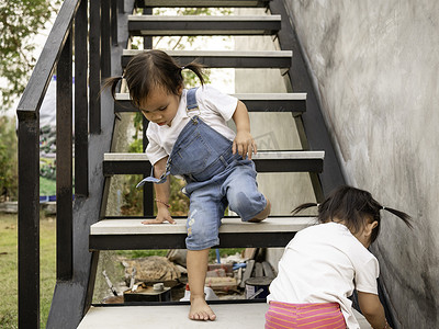 攀爬小孩摄影照片_亚洲小孩和妹妹试图自己爬楼梯。
