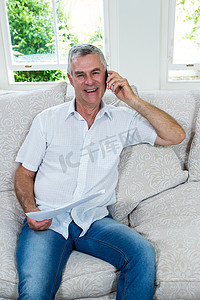 老人坐在沙发上摄影照片_老人坐在沙发上用手机聊天的肖像