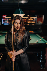 魅影汽车俱乐部摄影照片_一个手里拿着球杆的女孩站在台球俱乐部里。俄罗斯台球