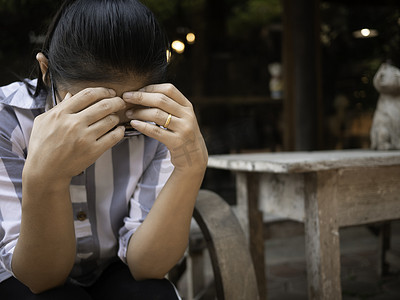 流泪摄影照片_亚洲年轻女子戴眼镜，眼睛发炎，流泪。