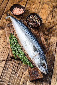 咸水杂鱼煲摄影照片_未加工的咸水鱼鲭鱼在木切板上与百里香。