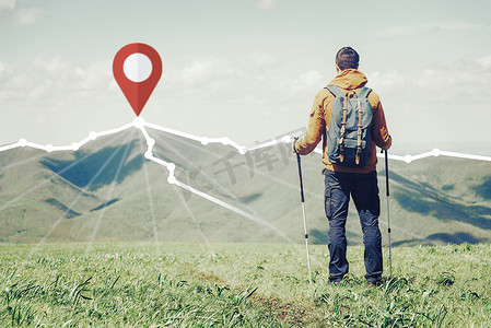 路线摄影照片_徒步旅行者站在路线前面，在山脊的山顶上有定位 GPS 引脚。