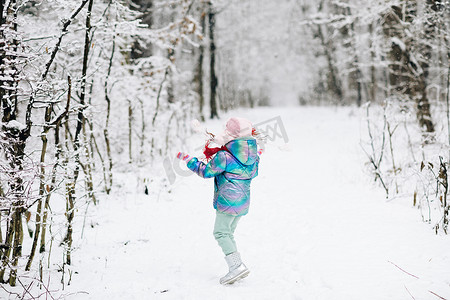 冬天的小女孩在户外公园的雪地里玩耍。
