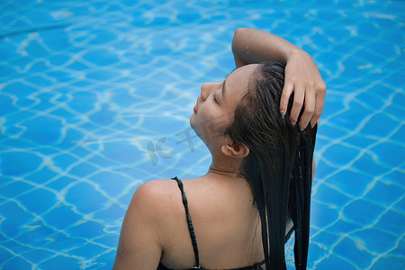 美丽的东南亚女人在泳池放松。