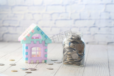 罐子里的硬币和桌子上的房子，房屋财务的概念