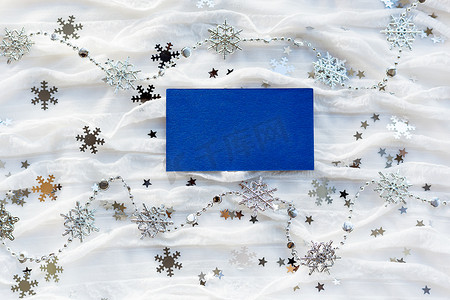 与装饰闪闪发光的雪花的冬天背景和空的一张蓝纸为您的文本。