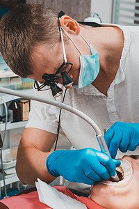 切除术摄影照片_病人和牙医，咀嚼牙的检查和治疗，旧填充物的去除，牵开器的使用。