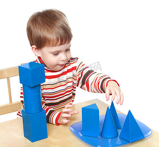 小男孩坐在桌子旁玩立方体和圆锥体，蒙特梭