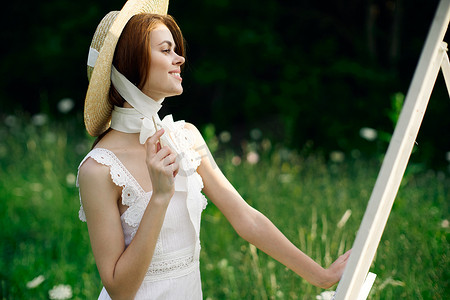学生画画摄影照片_穿白裙子的女人在自然画架上画了一幅画