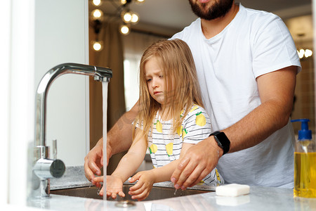 父亲和女儿在厨房的水槽上方洗手