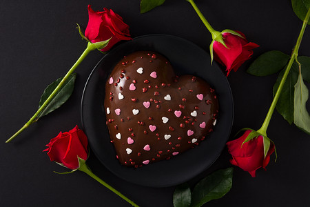 红玫瑰蛋糕摄影照片_情人节或母亲节的心形蛋糕和红玫瑰