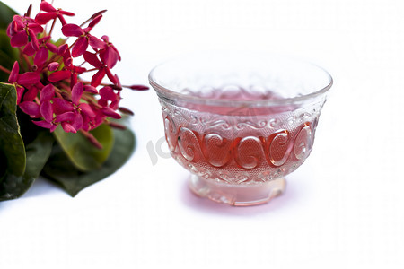 五角星闪摄影照片_红色五角花或埃及星花或茉莉花在白色上的特写，其提取的草药和药用茶放在一个小透明玻璃碗中。