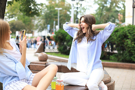 快乐的女朋友们正在城里的长凳上互相拍照。