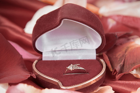 新婚玫瑰摄影照片_亮红色背景中的钻戒和玫瑰花瓣