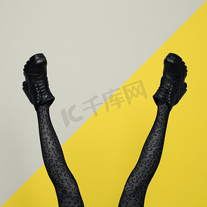 新的灰色女靴子，长着细长的女性腿，穿着灰色紧身衣，与黄色和灰色背景隔离。