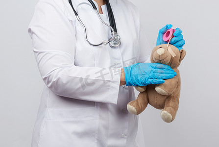 一件白色外套和蓝色乳汁手套的女性医生举起额头