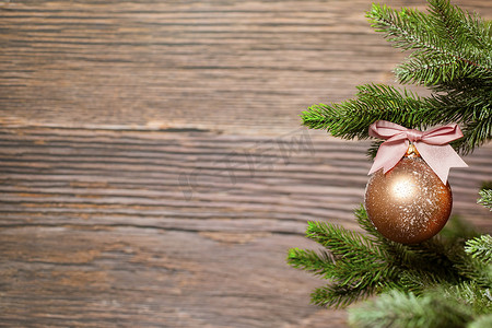 粉色蝴蝶结摄影照片_圣诞树枝上挂着闪闪发光的圣诞小玩意，粉色蝴蝶结，木质背景，有复制空间，节日概念