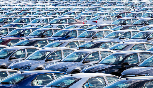 在阳光明媚的日子里，一排排新车停在一家汽车厂的配送中心。