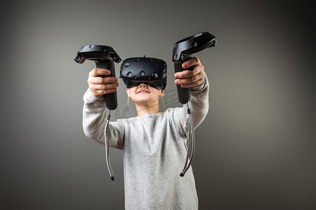 虚拟现实现实摄影照片_可爱的小女孩戴着虚拟现实眼镜和两个操纵杆玩游戏
