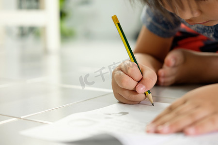 书法写字格摄影照片_亚洲男孩在地板上写字。