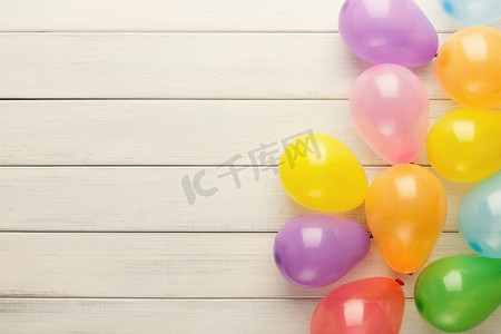 白色质朴木材上的彩色气球，生日背景，顶视图