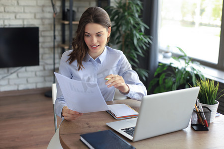 财务办公摄影照片_快乐的女企业家坐在办公桌前，阅读邮政信件中的好消息。