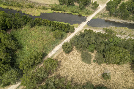小溪线条摄影照片_穿过绿色乡村景观的小溪和道路