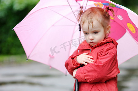 秋天雨天可爱的蹒跚学步的女孩