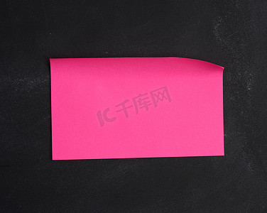 粘在黑色黑板上的空白纸粉红色贴纸