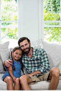开朗的父亲和女儿坐在沙发上的画像