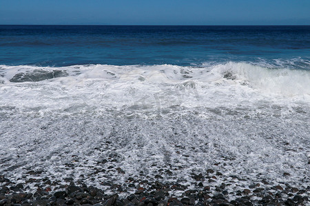 大海浪拍岸摄影照片_海上三四点小风暴，海浪拍岸有大卵石。