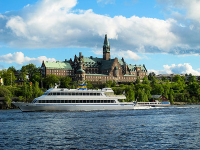 瑞典斯德哥尔摩美丽建筑的背景下，旅游游船漂浮在蓝色的湖水上