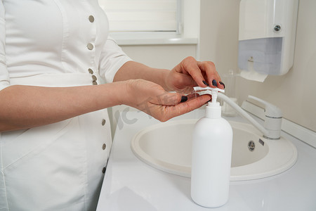 在水槽里洗手之前，女性手压在肥皂瓶上的剪影