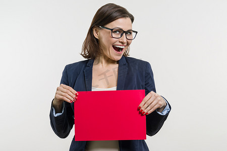 女性红色海报摄影照片_白色背景上拿着红色纸片的微笑女人