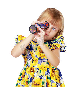 小女孩背景摄影照片_一个小女孩看着望远镜或万花筒。