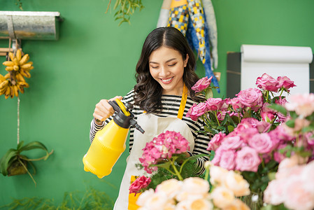 鲜花女摄影照片_在花店工作的可爱集中的年轻亚洲女花匠