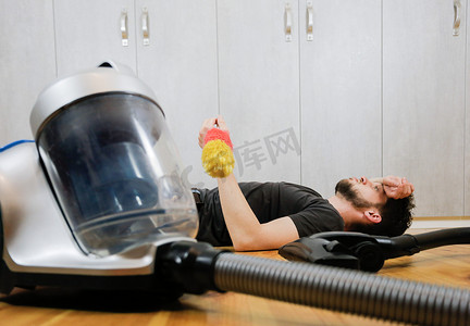 整理客厅摄影照片_一个有吸尘器的男人厌倦了打扫房子