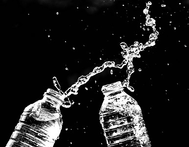 黑色，黑色摄影照片_在黑色背景上从瓶子里溅出的新鲜纯净水。