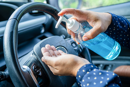 新常态，亚洲职业女性用蓝色酒精消毒凝胶洗手，以保护车内冠状病毒的安全。