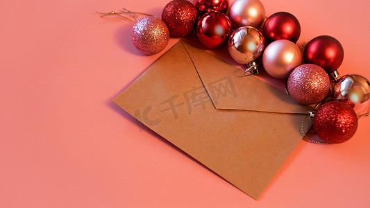 牛皮纸信封，粉色背景上有圣诞红色和粉色球