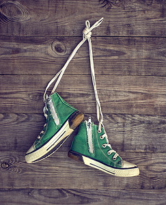 一双旧的绿色纺织运动鞋挂在鞋带上