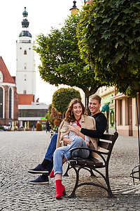 美丽的年轻夫妇拥抱在欧洲小镇的长凳上。