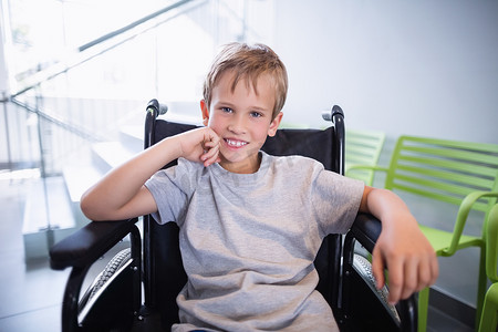 病人移动摄影照片_坐在轮椅上微笑的男孩病人的肖像
